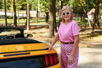 Photo of Stylish senior woman in sunglasses near modern cabriolet outdoors