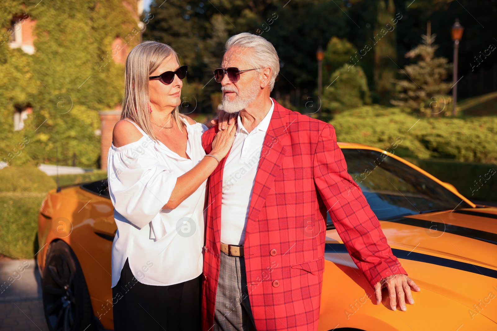 Photo of Stylish senior couple in sunglasses near modern cabriolet outdoors
