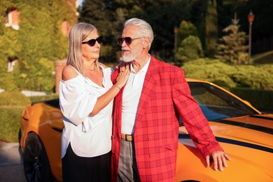 Photo of Stylish senior couple in sunglasses near modern cabriolet outdoors