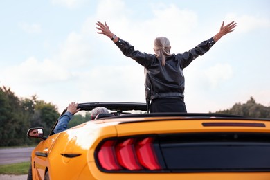 Photo of Senior couple enjoying cabriolet ride in city, back view. Woman with wide open arms