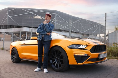 Photo of Stylish senior man near modern cabriolet outdoors