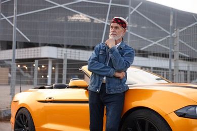 Photo of Stylish senior man near modern cabriolet outdoors