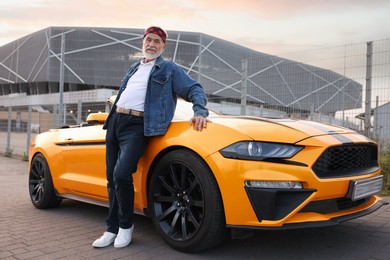 Photo of Stylish senior man near modern cabriolet outdoors
