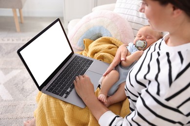 Photo of Telehealth. Mother with her baby having online consultation with doctor by laptop on sofa at home, closeup