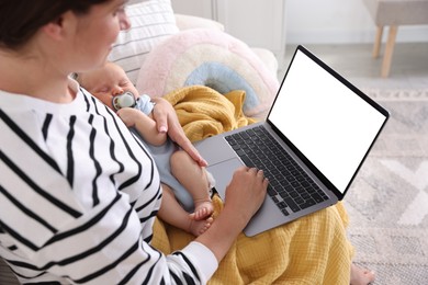 Photo of Telehealth. Mother with her baby having online consultation with doctor by laptop on sofa at home, closeup