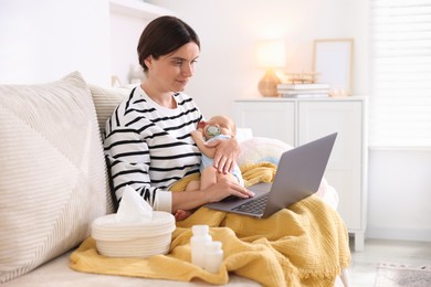 Photo of Telehealth. Mother with her baby having online consultation with doctor by laptop on sofa at home