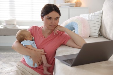 Photo of Telehealth. Mother with her baby leaning on sofa and having online consultation with doctor at home