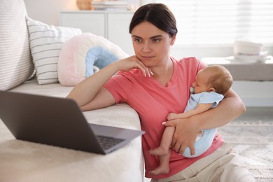 Photo of Telehealth. Mother with her baby leaning on sofa and having online consultation with doctor at home