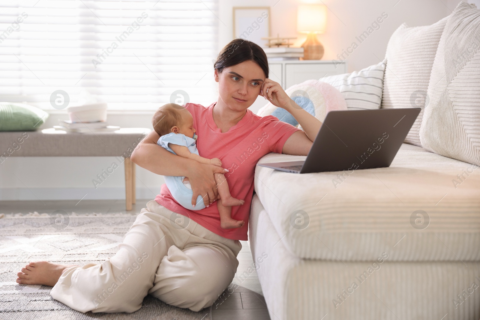 Photo of Telehealth. Mother with her baby leaning on sofa and having online consultation with doctor at home