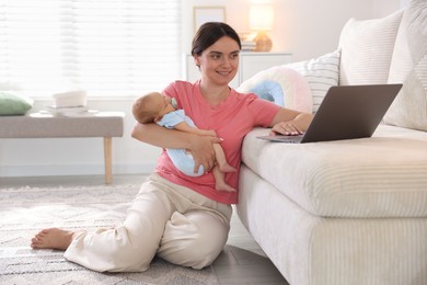 Photo of Telehealth. Smiling mother with her baby leaning on sofa and having online consultation with doctor at home