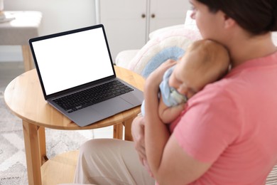 Photo of Telehealth. Mother with her baby having online consultation with doctor at table indoors