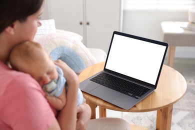 Photo of Telehealth. Mother with her baby having online consultation with doctor at table indoors