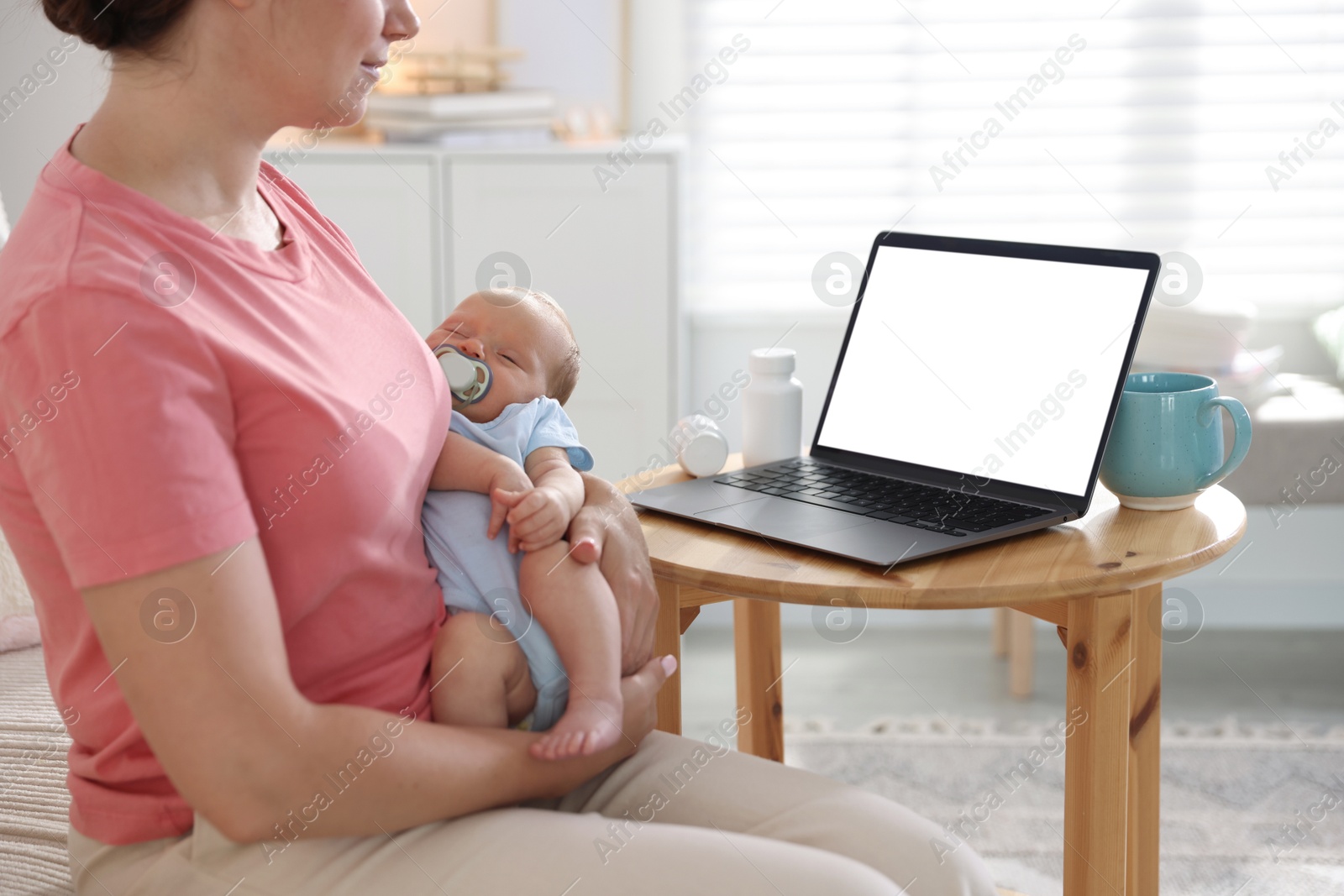 Photo of Telehealth. Mother with her baby having online consultation with doctor at table indoors, closeup
