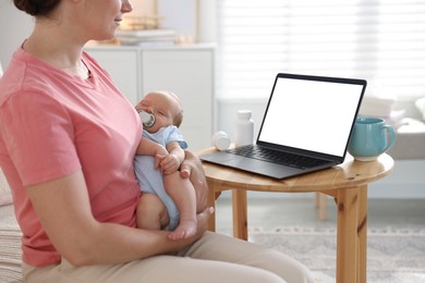 Photo of Telehealth. Mother with her baby having online consultation with doctor at table indoors, closeup