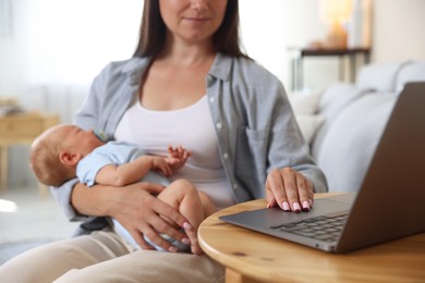 Photo of Telehealth. Mother with her baby having online consultation with doctor at table indoors, closeup