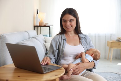 Photo of Telehealth. Smiling mother with her baby having online consultation with doctor at table indoors