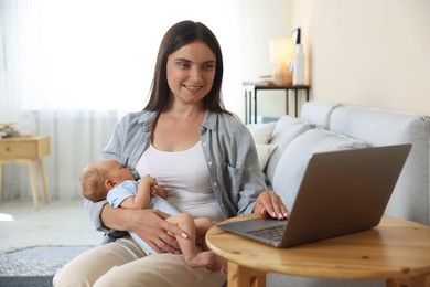Photo of Telehealth. Smiling mother with her baby having online consultation with doctor at table indoors
