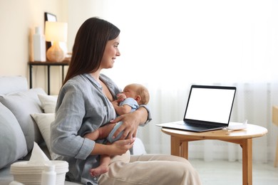 Photo of Telehealth. Smiling mother with her baby having online consultation with doctor by laptop on sofa at home