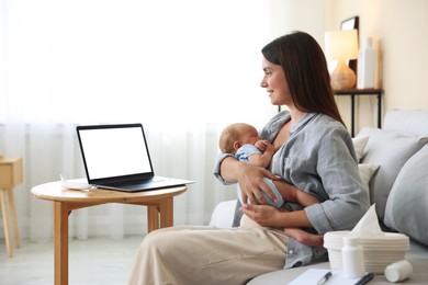 Photo of Telehealth. Smiling mother with her baby having online consultation with doctor by laptop on sofa at home