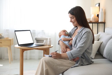 Photo of Telehealth. Smiling mother with her baby having online consultation with doctor by laptop on sofa at home