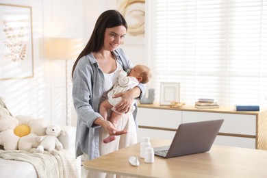 Photo of Telehealth. Smiling mother with her baby having online consultation with doctor at table indoors