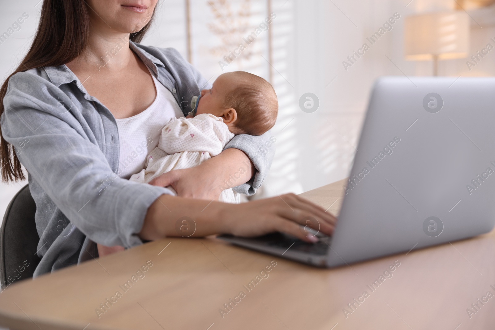 Photo of Telehealth. Mother with her baby having online consultation with doctor at table indoors, closeup