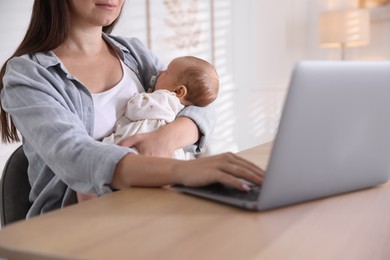 Photo of Telehealth. Mother with her baby having online consultation with doctor at table indoors, closeup