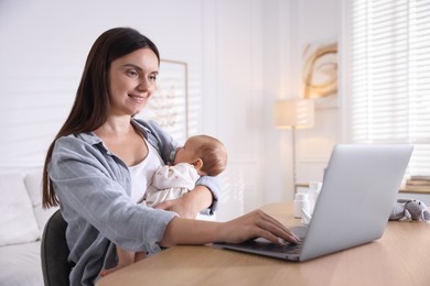 Photo of Telehealth. Smiling mother with her baby having online consultation with doctor at table indoors