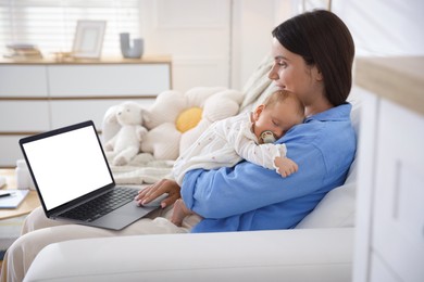 Photo of Telehealth. Smiling mother with her baby having online consultation with doctor by laptop on sofa at home