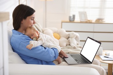 Photo of Telehealth. Smiling mother with her baby having online consultation with doctor by laptop on sofa at home