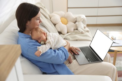 Photo of Telehealth. Smiling mother with her baby having online consultation with doctor by laptop on sofa at home
