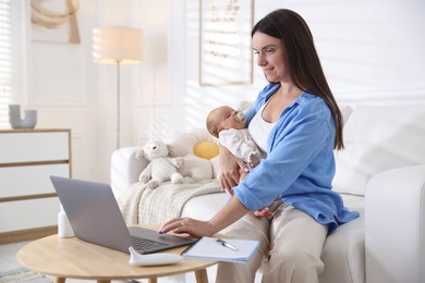 Photo of Telehealth. Smiling mother with her baby having online consultation with doctor by laptop on sofa at home