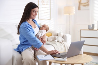 Photo of Telehealth. Smiling mother with her baby having online consultation with doctor by laptop on sofa at home