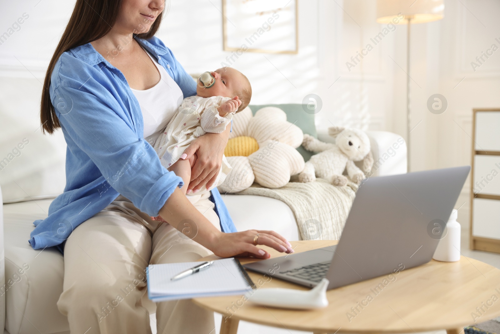 Photo of Telehealth. Mother with her baby having online consultation with doctor on sofa indoors, closeup