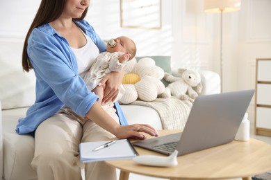 Photo of Telehealth. Mother with her baby having online consultation with doctor on sofa indoors, closeup
