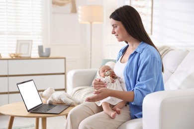 Photo of Telehealth. Smiling mother with her baby having online consultation with doctor by laptop on sofa at home