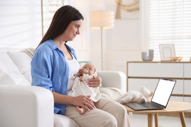 Photo of Telehealth. Mother with her baby having online consultation with doctor on sofa indoors