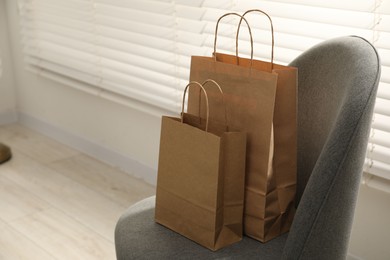Photo of Paper bags on armchair indoors. Space for text