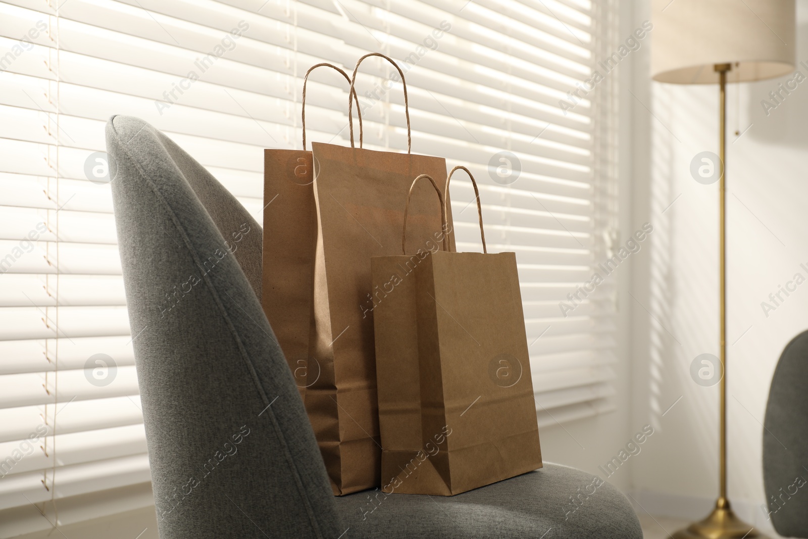 Photo of Paper bags on armchair near window indoors