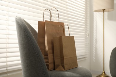 Photo of Paper bags on armchair near window indoors