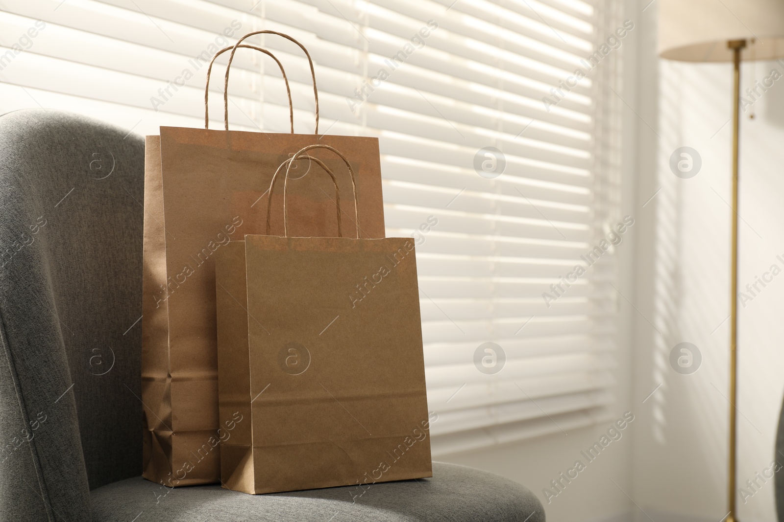 Photo of Paper bags on armchair indoors. Space for text