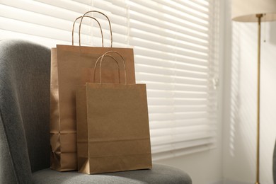Photo of Paper bags on armchair indoors. Space for text