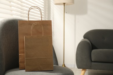 Photo of Paper bags on armchair indoors. Space for text