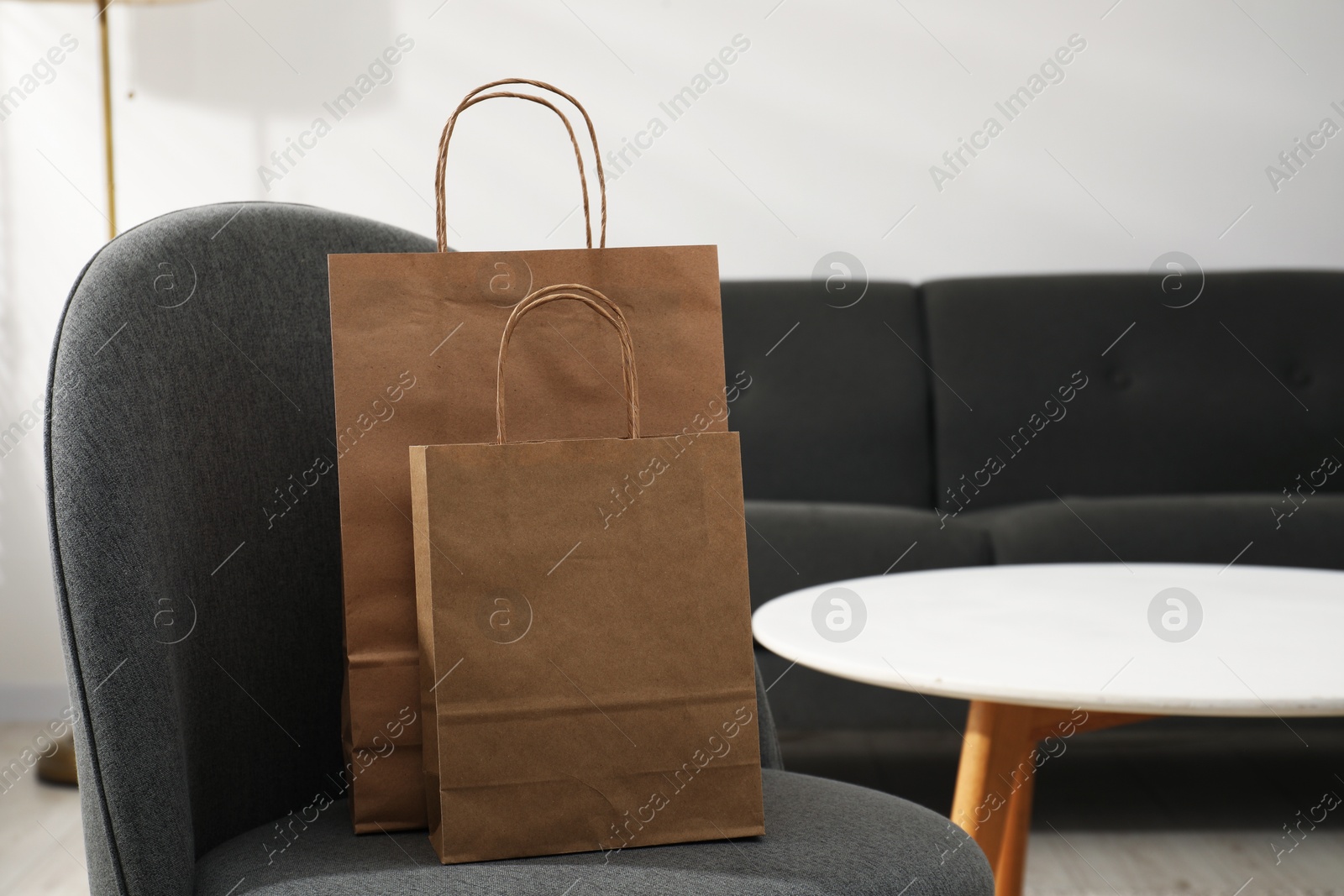 Photo of Paper bags on armchair indoors. Space for text