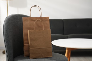 Photo of Paper bags on armchair indoors. Space for text
