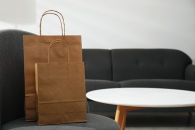 Photo of Paper bags on armchair indoors. Space for text