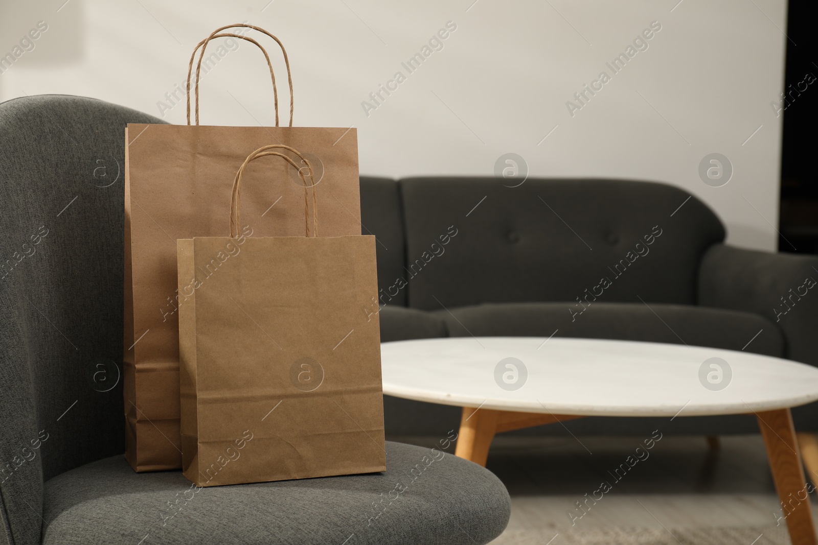 Photo of Paper bags on armchair indoors. Space for text