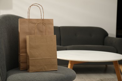 Photo of Paper bags on armchair indoors. Space for text