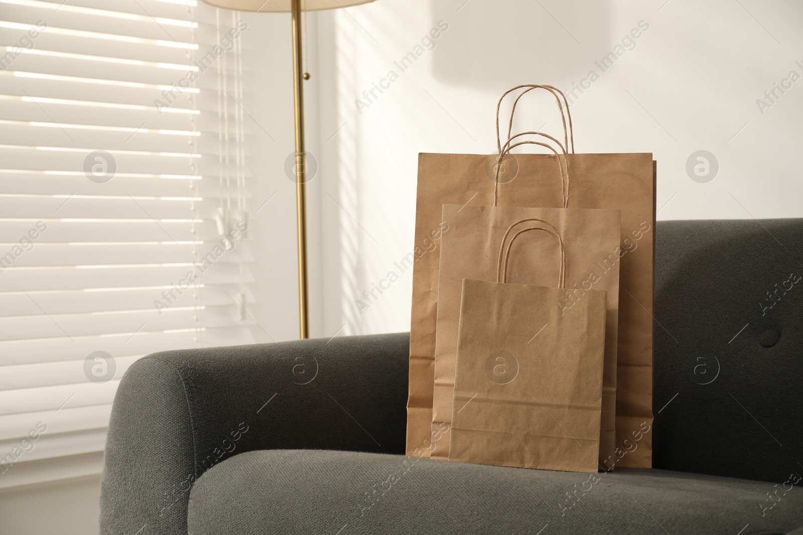 Photo of Paper bags on grey sofa indoors. Space for text