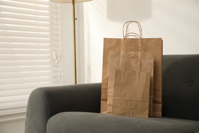 Photo of Paper bags on grey sofa indoors. Space for text